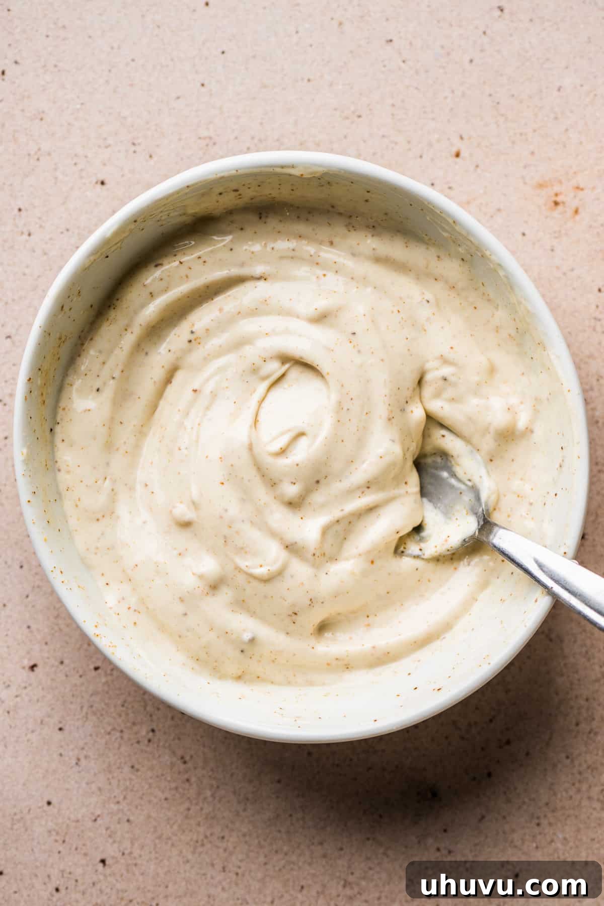 A bowl of creamy mayo sauce for topping elote.