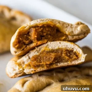 Pumpkin Empanadas cut in half with pumpkin filling exposed.