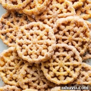 Buñuelos covered in cinnamon sugar on a baking sheet lined with paper towels.