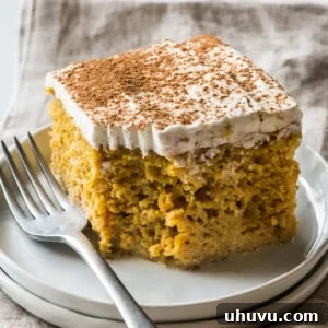 A slice of pumpkin tres leches cake topped with whipped cream and garnished with a dusting of pumpkin spice seasoning.