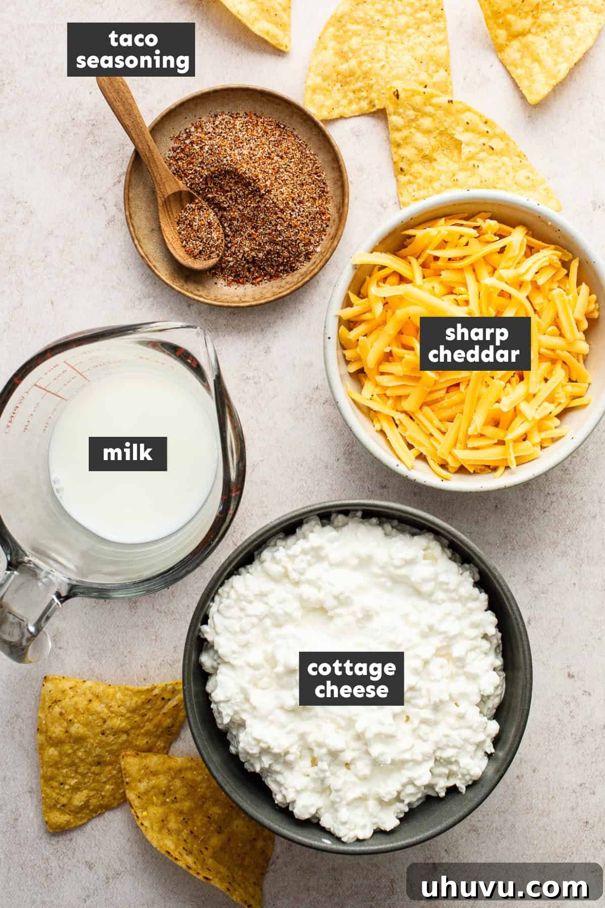 Creamy Cottage Queso 4 A selection of fresh ingredients laid out on a table, including cottage cheese, milk, taco seasoning, and shredded cheddar cheese, ready to be prepared into cottage cheese queso.