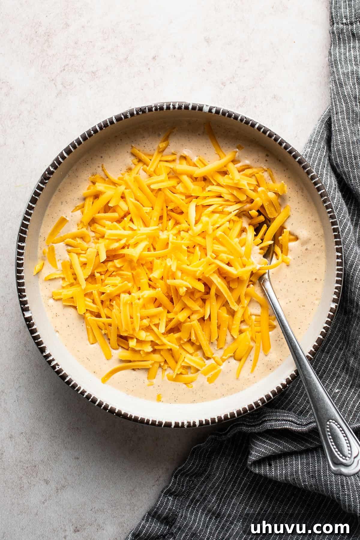 Creamy Cottage Queso 7 Step 3: Shredded cheese stirred into the blended mixture in a microwave-safe bowl.