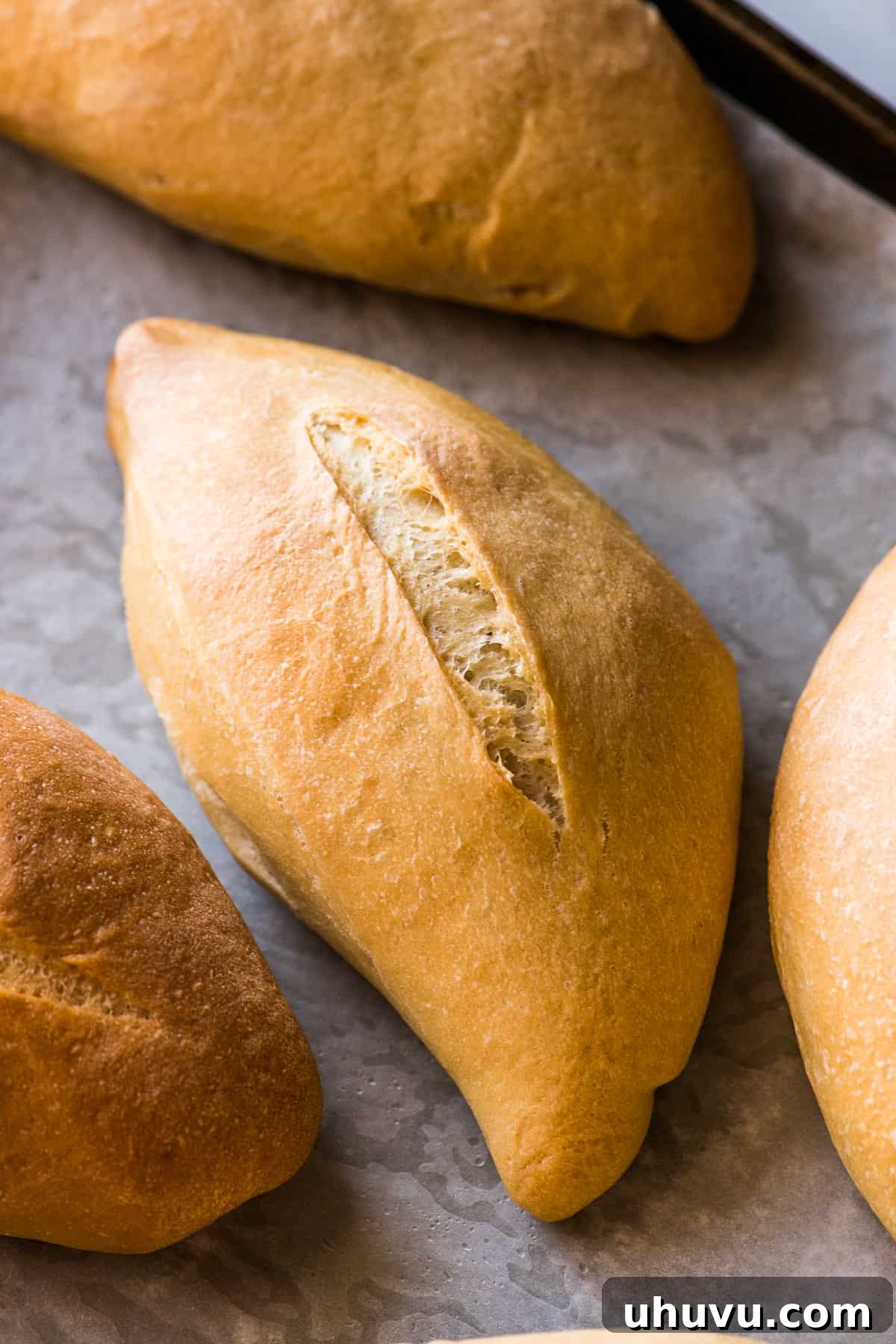 Mexican Bolillo Rolls 11 Baked bolillo with a golden brown crust on a baking sheet ready to eat.