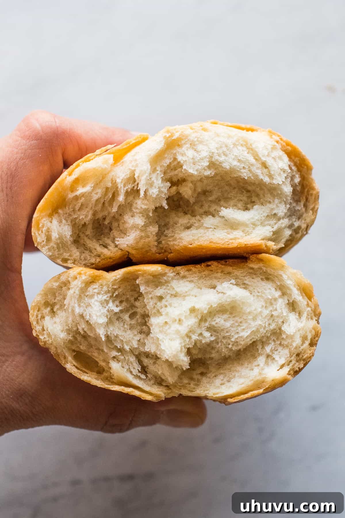 Mexican Bolillo Rolls 12 A bolillo bread cut in half to show the soft white bread inside in contrast to the crispy golden brown crust on the outside.