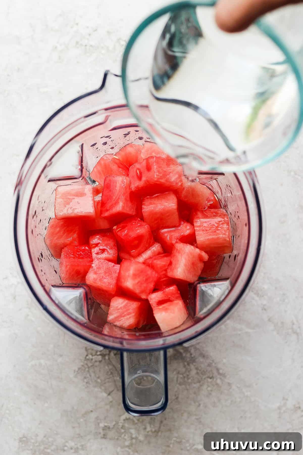 Cool Watermelon Refreshment 4 Water being poured into a blender with diced watermelon in it.