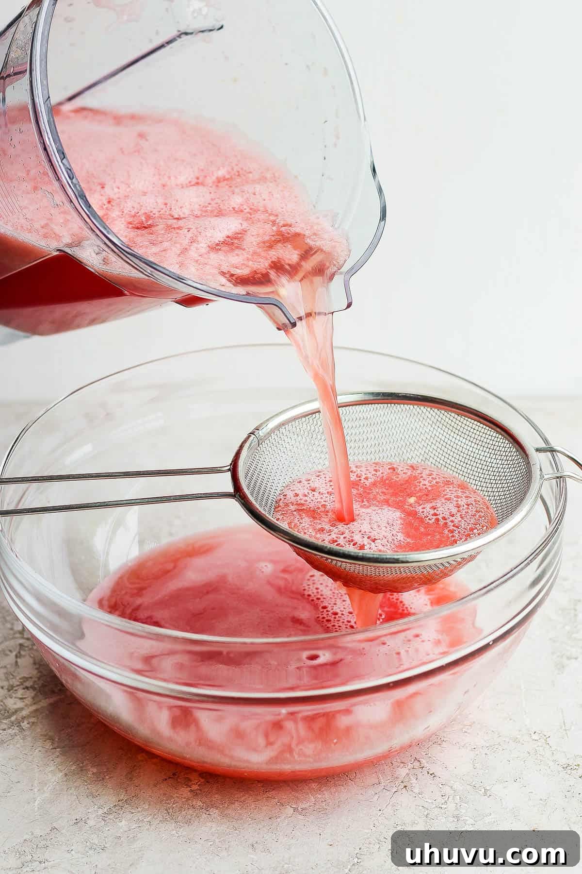 Cool Watermelon Refreshment 6 Watermelon agua fresca being poured through a strainer.