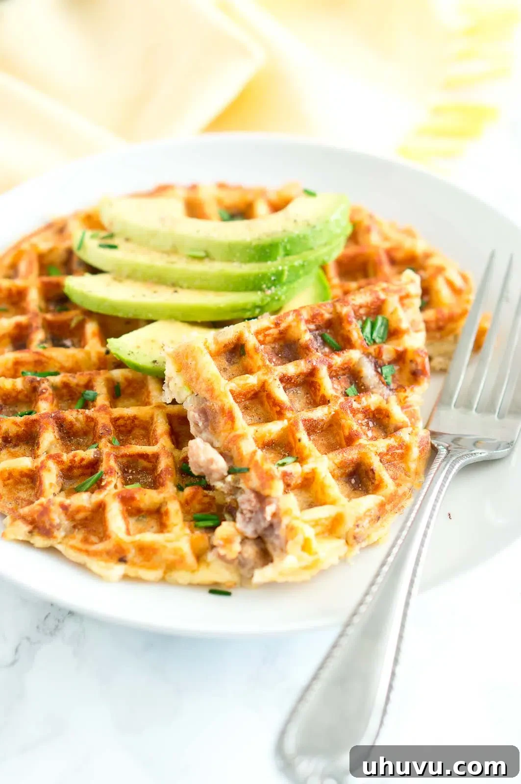 Sausage and Potato Waffles plated with fresh herbs and a side of greens