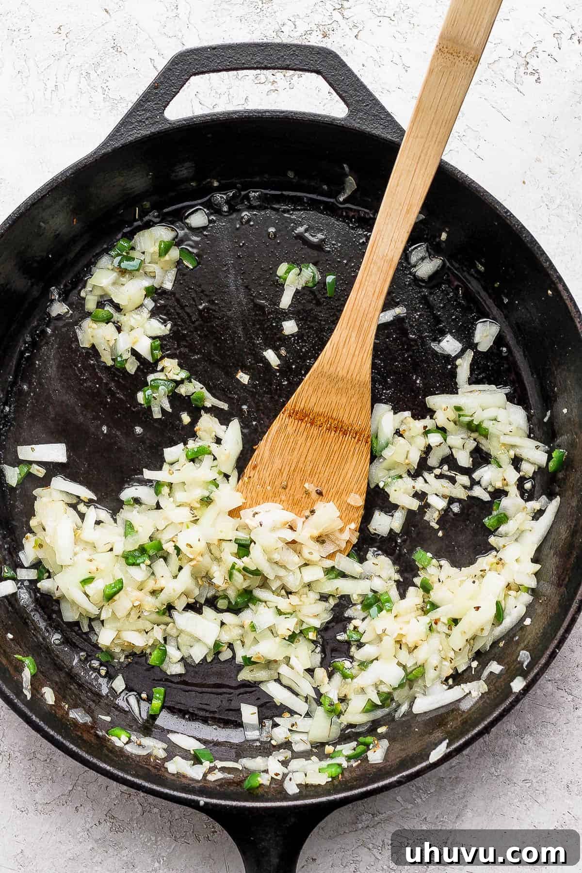 Velvety Frijoles 8 Onion, jalapeno, and garlic being sauteed in a skillet.