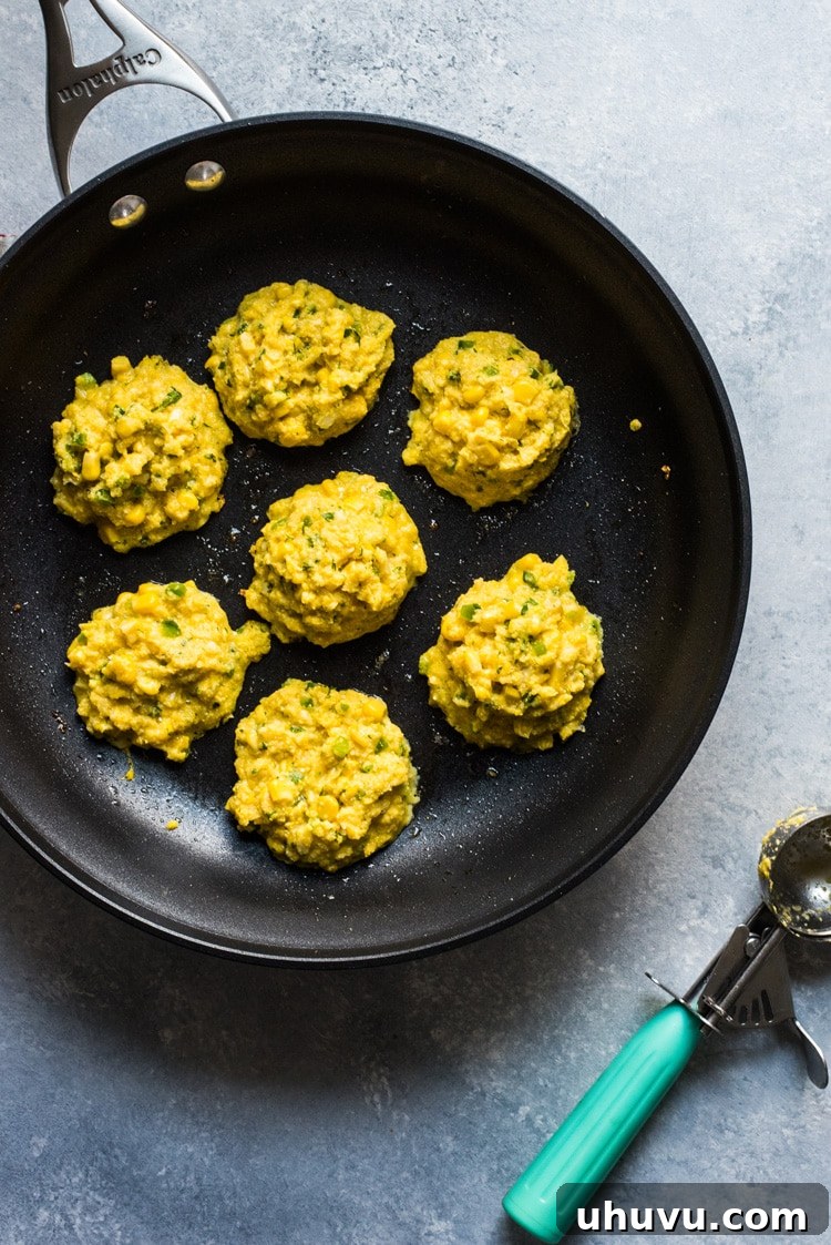 Close-up of a stack of golden brown Jalapeno Corn Cakes, showing their crispy texture and the corn kernels within.