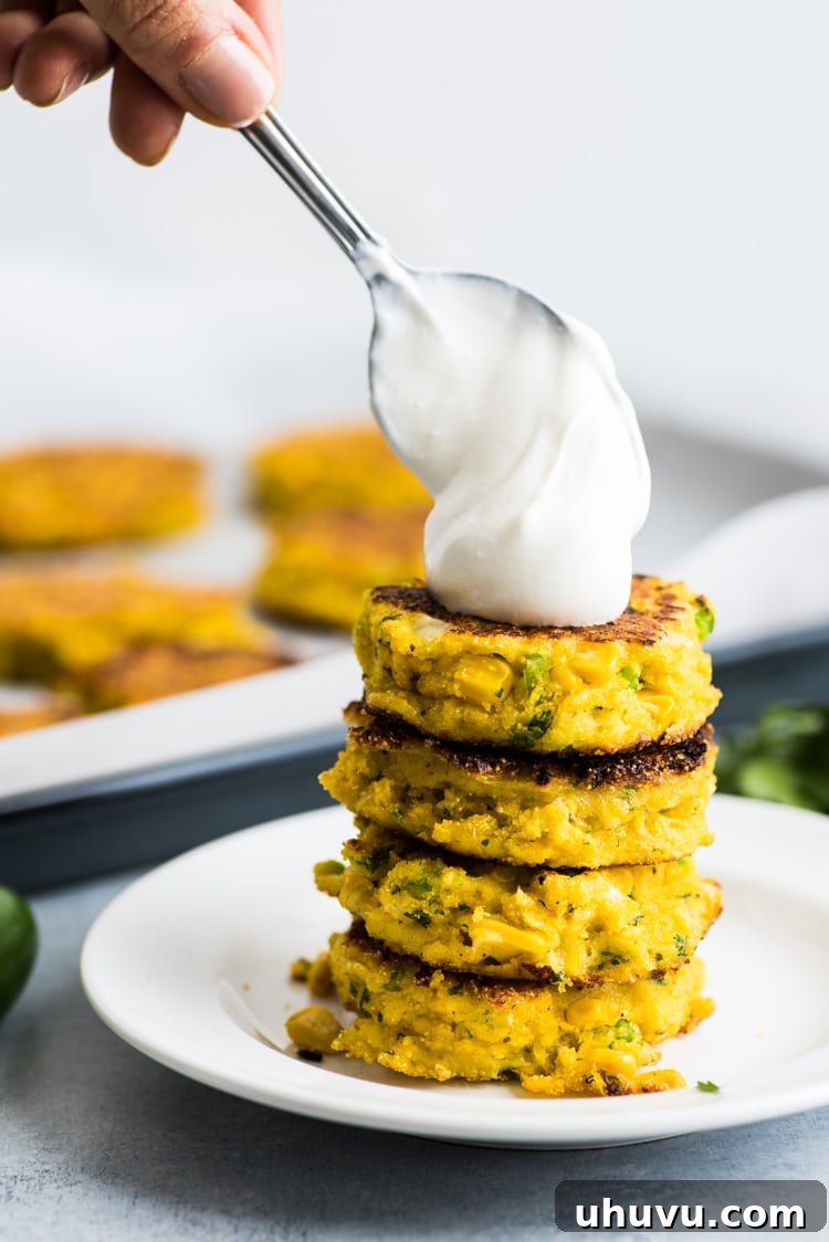 Two golden brown Jalapeno Corn Cakes cooking in a frying pan, showing the oil sizzling and the cakes browning beautifully.