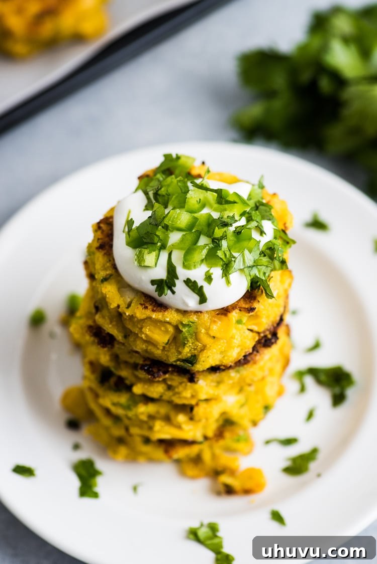 Zesty Jalapeno Corn Fritters 7 A beautifully plated dish of Jalapeno Corn Cakes, served with creamy sour cream and fresh cilantro garnish, ready to be enjoyed.