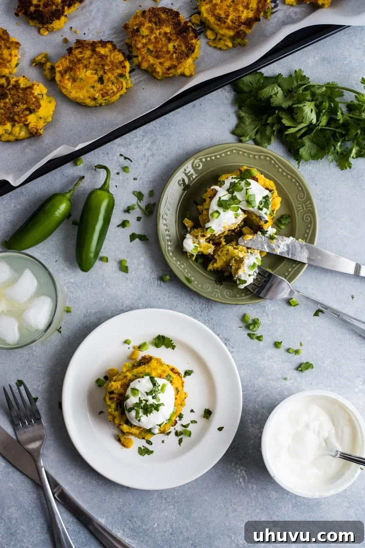 Zesty Jalapeno Corn Fritters 8 Jalapeno Corn Cakes served as a side dish, accompanied by a small bowl of dipping sauce and a scattering of fresh herbs.
