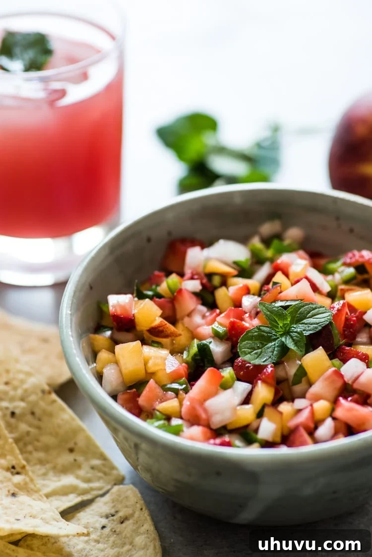 Serving of Peach Strawberry Salsa with a generous scoop of tortilla chips, demonstrating its perfect consistency for dipping.