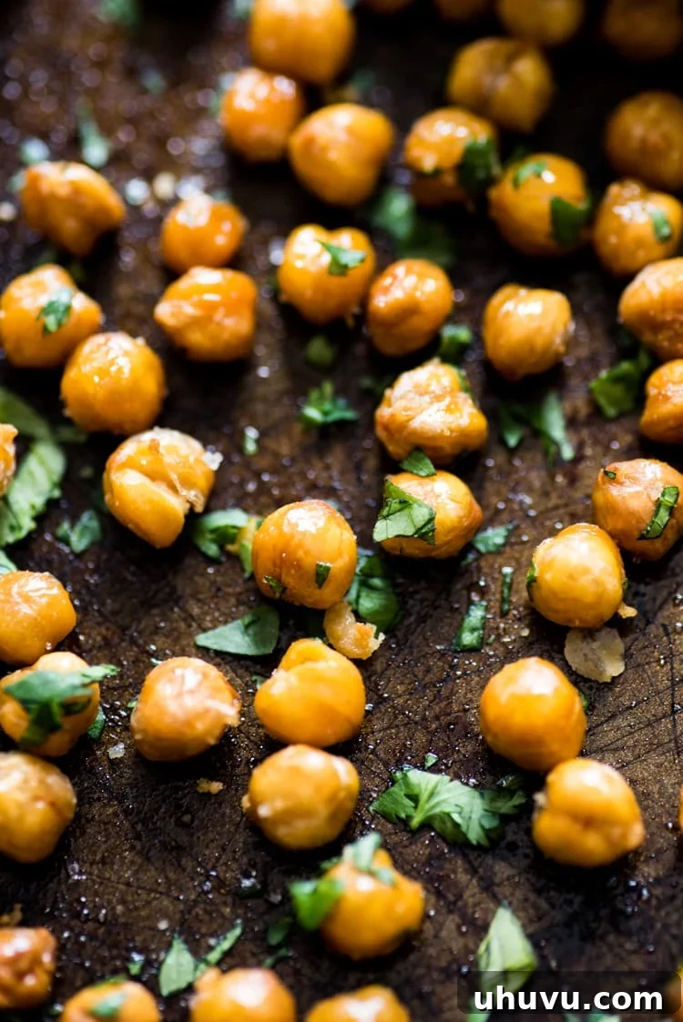 Zesty Cilantro Lime Roasted Chickpeas 2 A close-up shot of crispy Cilantro Lime Roasted Chickpeas in a bowl, garnished with fresh cilantro, a healthy and crunchy vegan snack option.