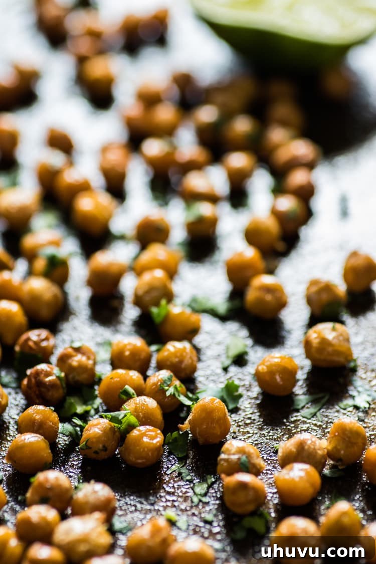 Zesty Cilantro Lime Roasted Chickpeas 4 A small white bowl filled with crunchy Cilantro Lime Roasted Chickpeas, placed on a rustic wooden board with a napkin, ready for snacking.