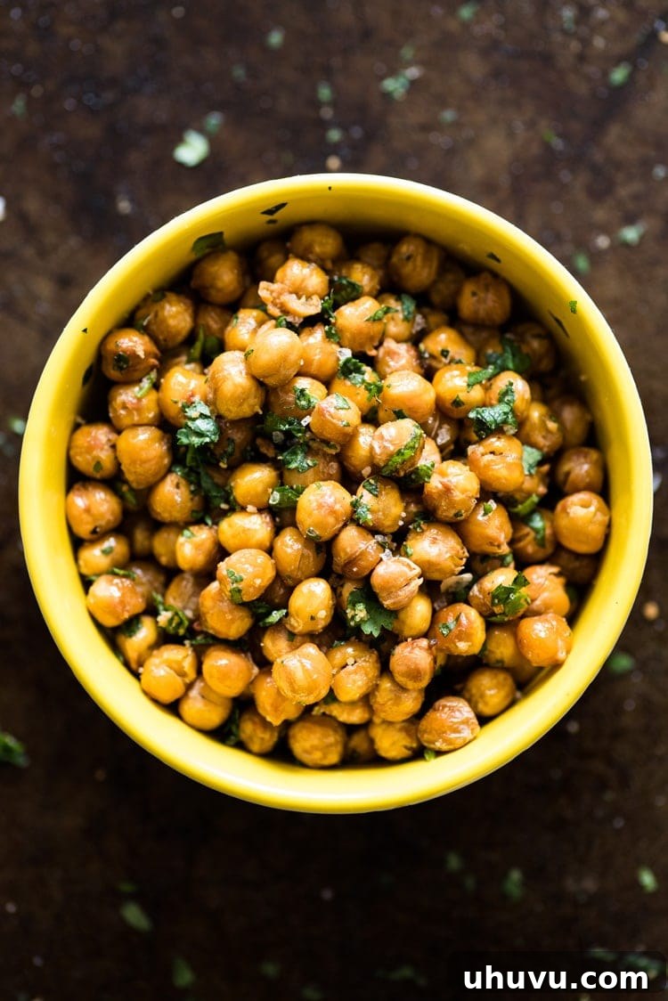 Zesty Cilantro Lime Roasted Chickpeas 5 A vibrant display of ingredients: fresh cilantro, cut limes, and olive oil next to a bowl of roasted chickpeas, emphasizing the natural components.