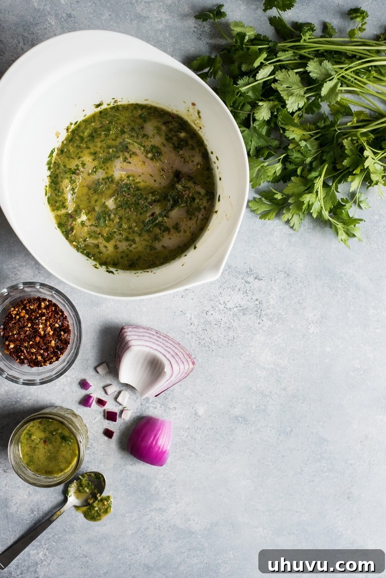 Sliced grilled chimichurri chicken and fresh avocado on a chopping board.