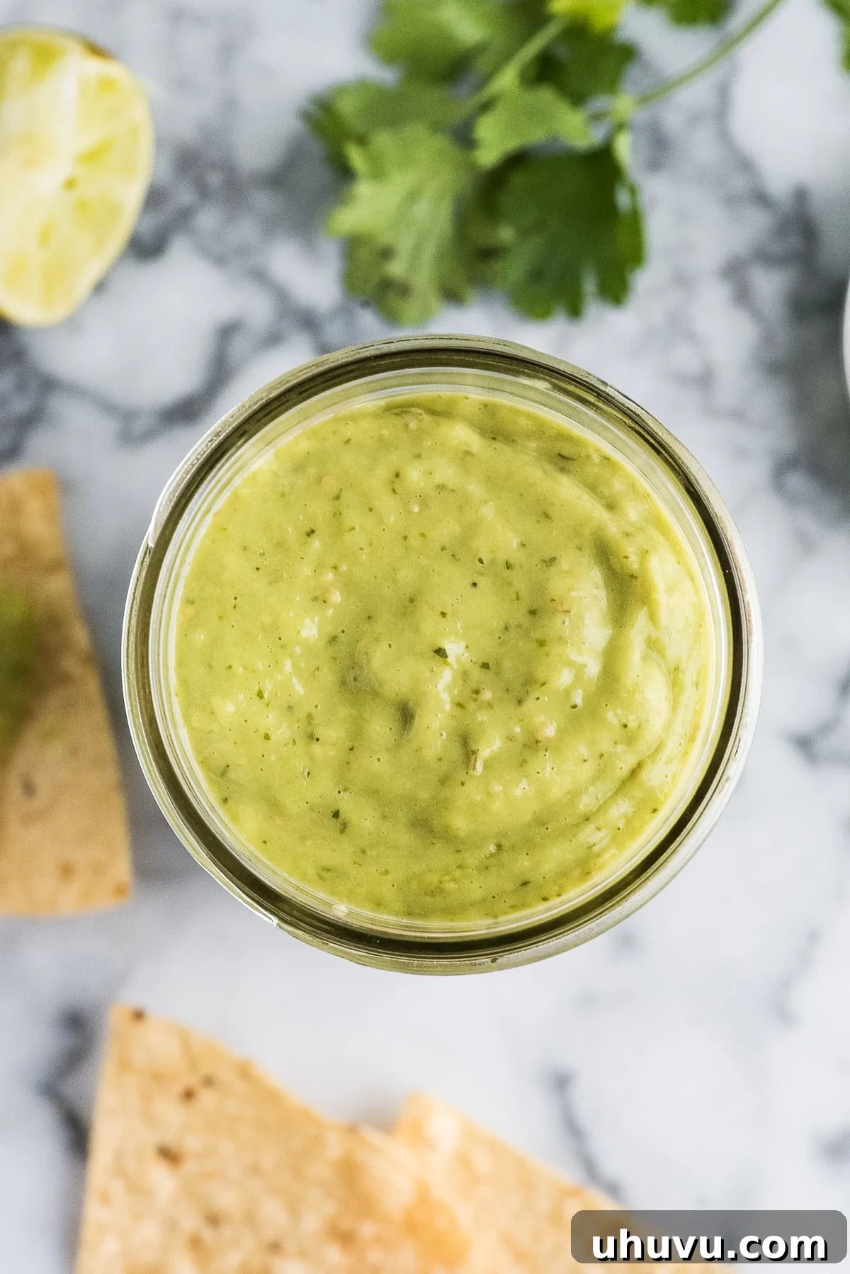 Creamy Verde Salsa 4 A jar of freshly made guacamole salsa placed elegantly on a wooden table, ready to be served.