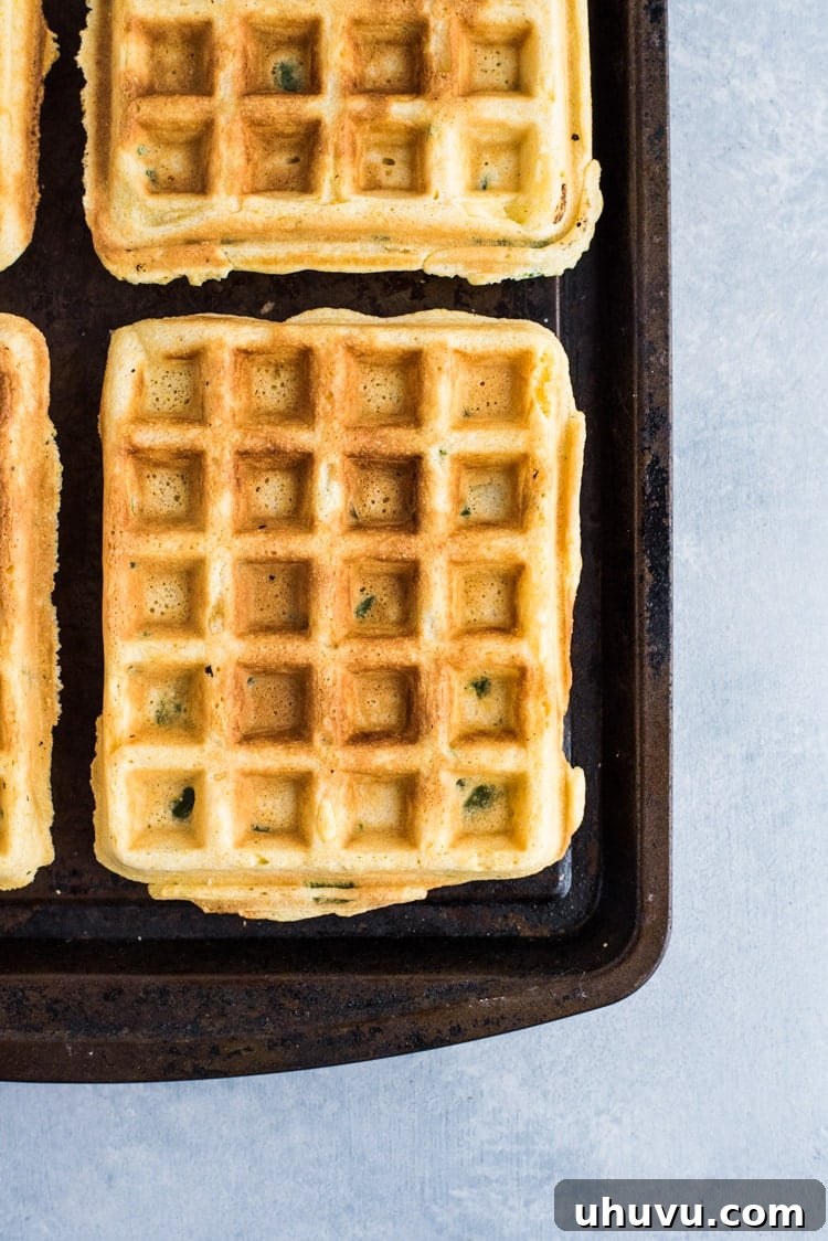 Close-up of savory Jalapeno Cornbread waffles with crispy chicken tenders and a generous drizzle of white gravy.