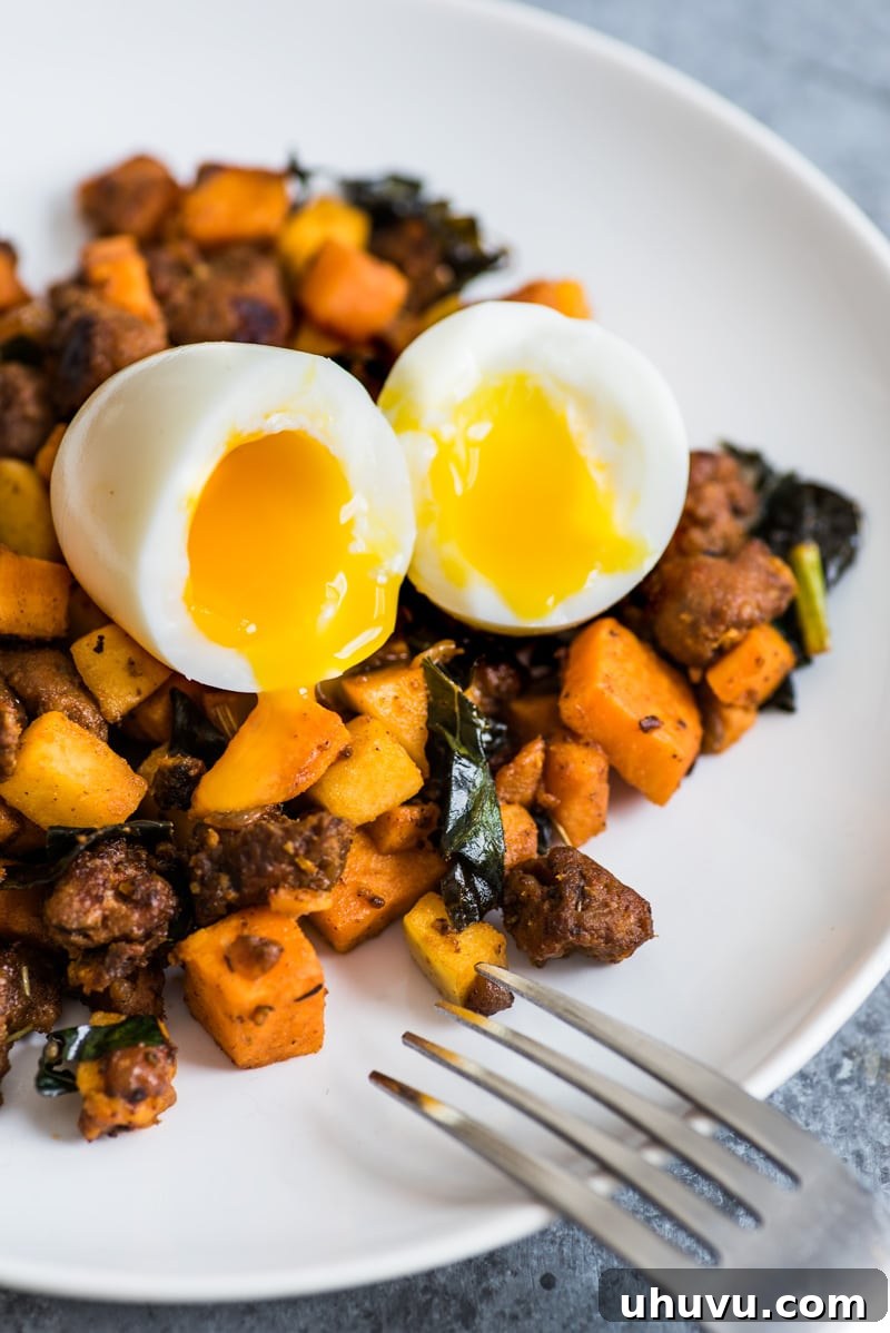 Mexican Chorizo Sweet Potato Hash with Jammy Eggs 4 A close-up of a soft-boiled egg being cut, revealing its perfectly runny yolk, ready to blend with the hearty Mexican Chorizo Sweet Potato Hash.