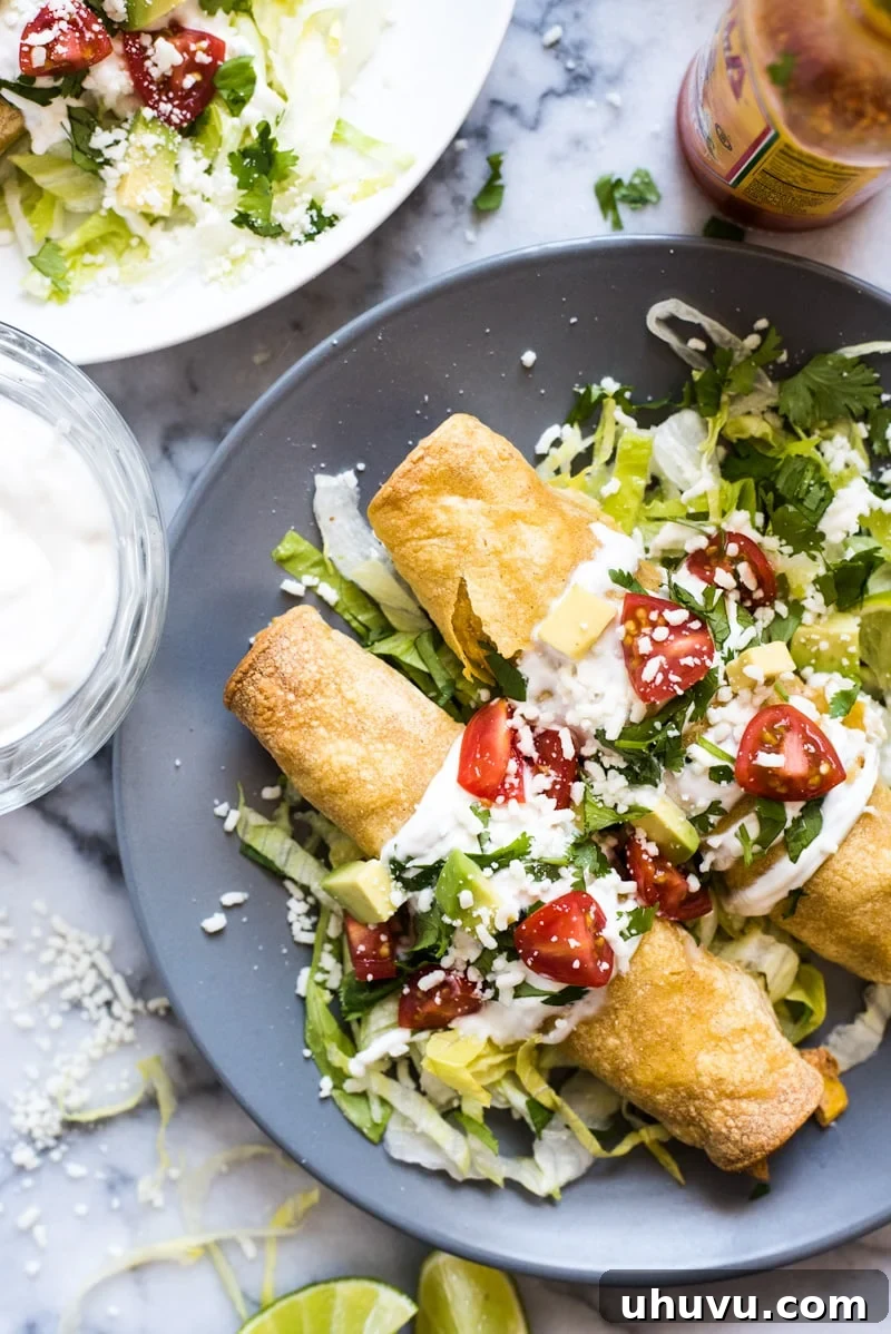 A plate of baked chicken taquitos, ready to be enjoyed with various dips and garnishes