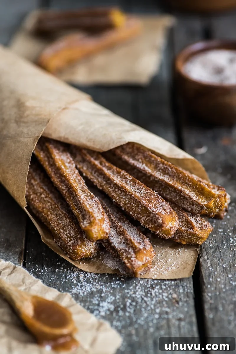 Close-up of golden brown Baked Pumpkin Churros dusted with sparkling cinnamon sugar, ready to be served. A healthier, baked version of the classic dessert.