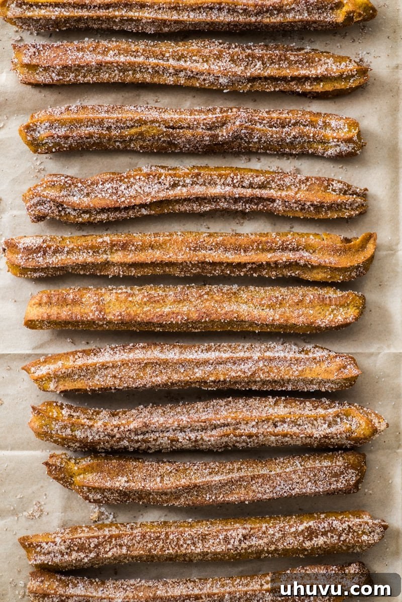 Piping Baked Pumpkin Churro dough onto a parchment-lined baking sheet, demonstrating the ease of preparation for this delicious seasonal dessert.