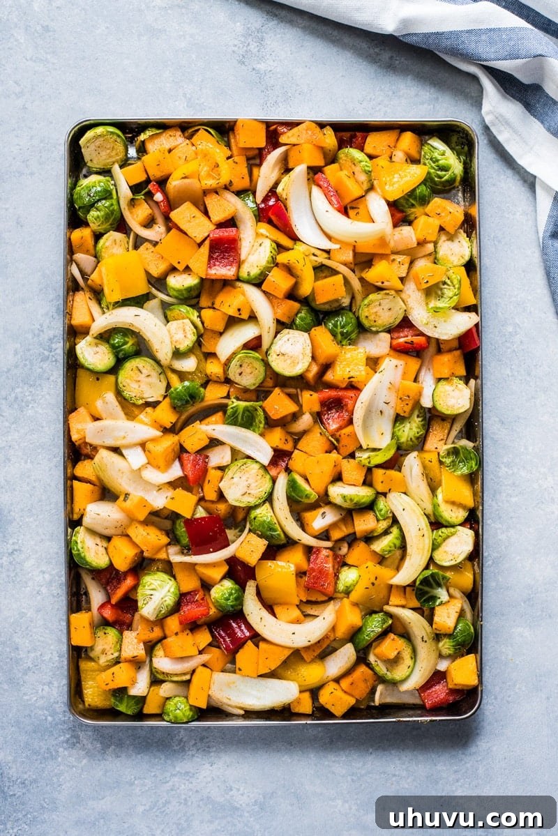 Close-up of perfectly roasted vegetables and sausages on a sheet pan.