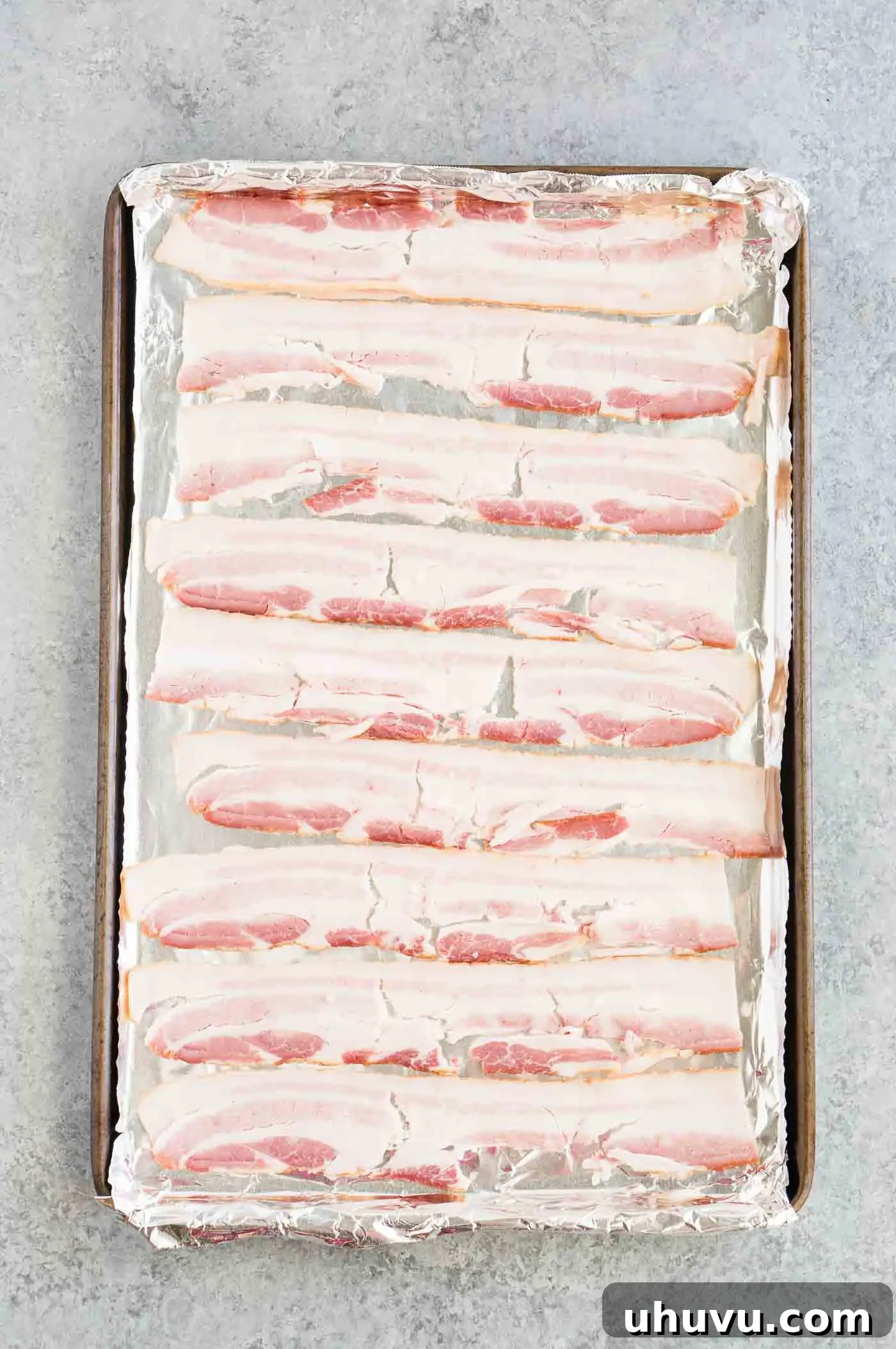 raw bacon on baking sheet with aluminum foil