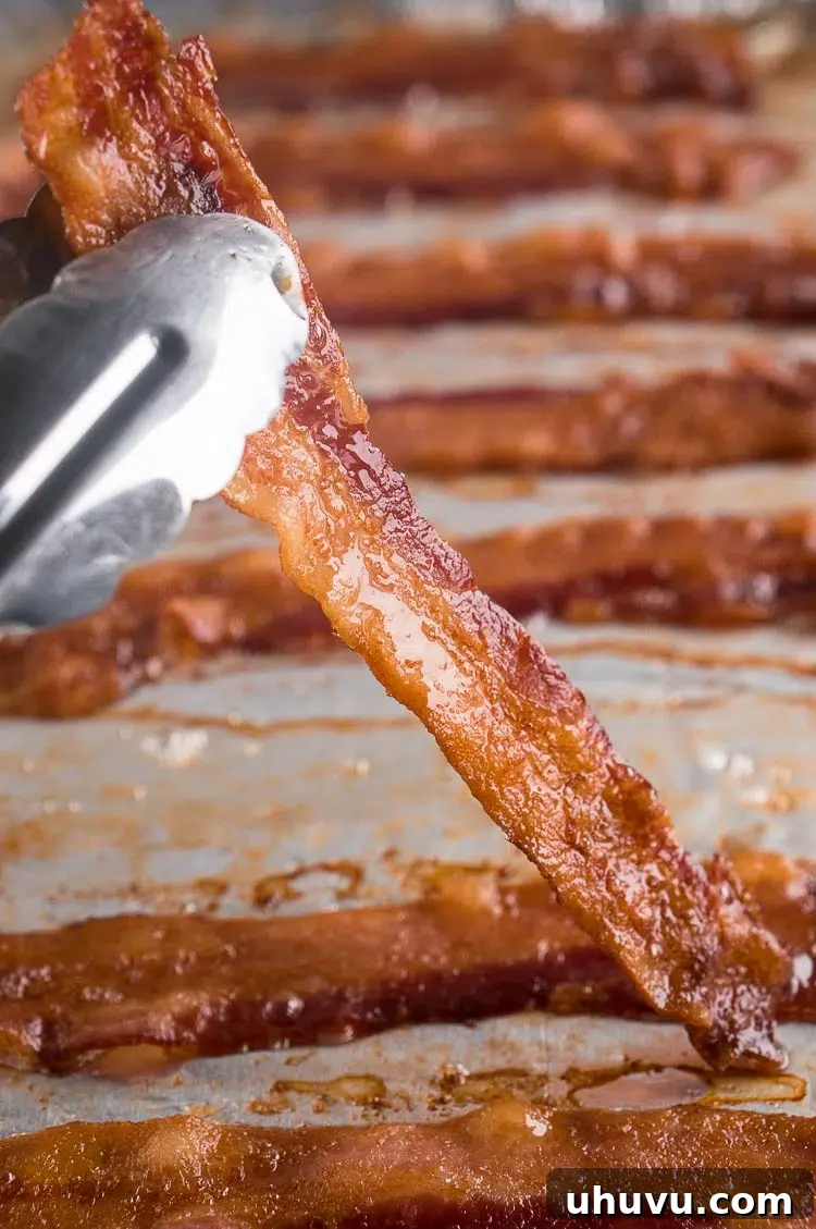 holding oven baked bacon slice with tongs