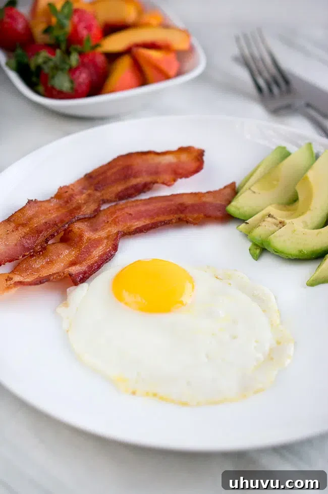Oven Baked Bacon with a fried egg and avocado on a plate