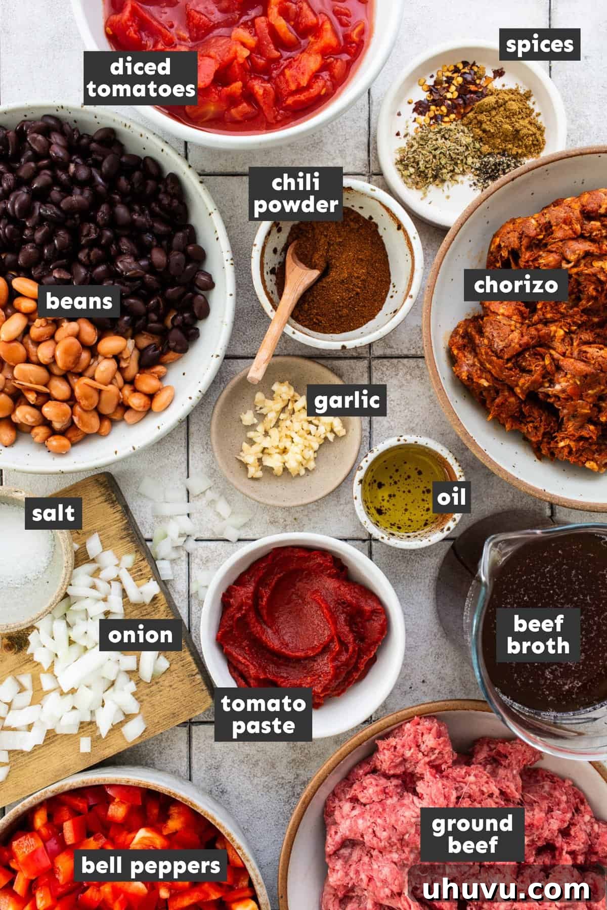 Chorizo Kick Chili 3 A collection of fresh, high-quality ingredients laid out on a wooden surface, including Mexican chorizo, ground beef, bell peppers, onions, garlic, canned beans, diced tomatoes, tomato paste, and a selection of dried spices. The essential building blocks for this easy Chorizo Chili meal.