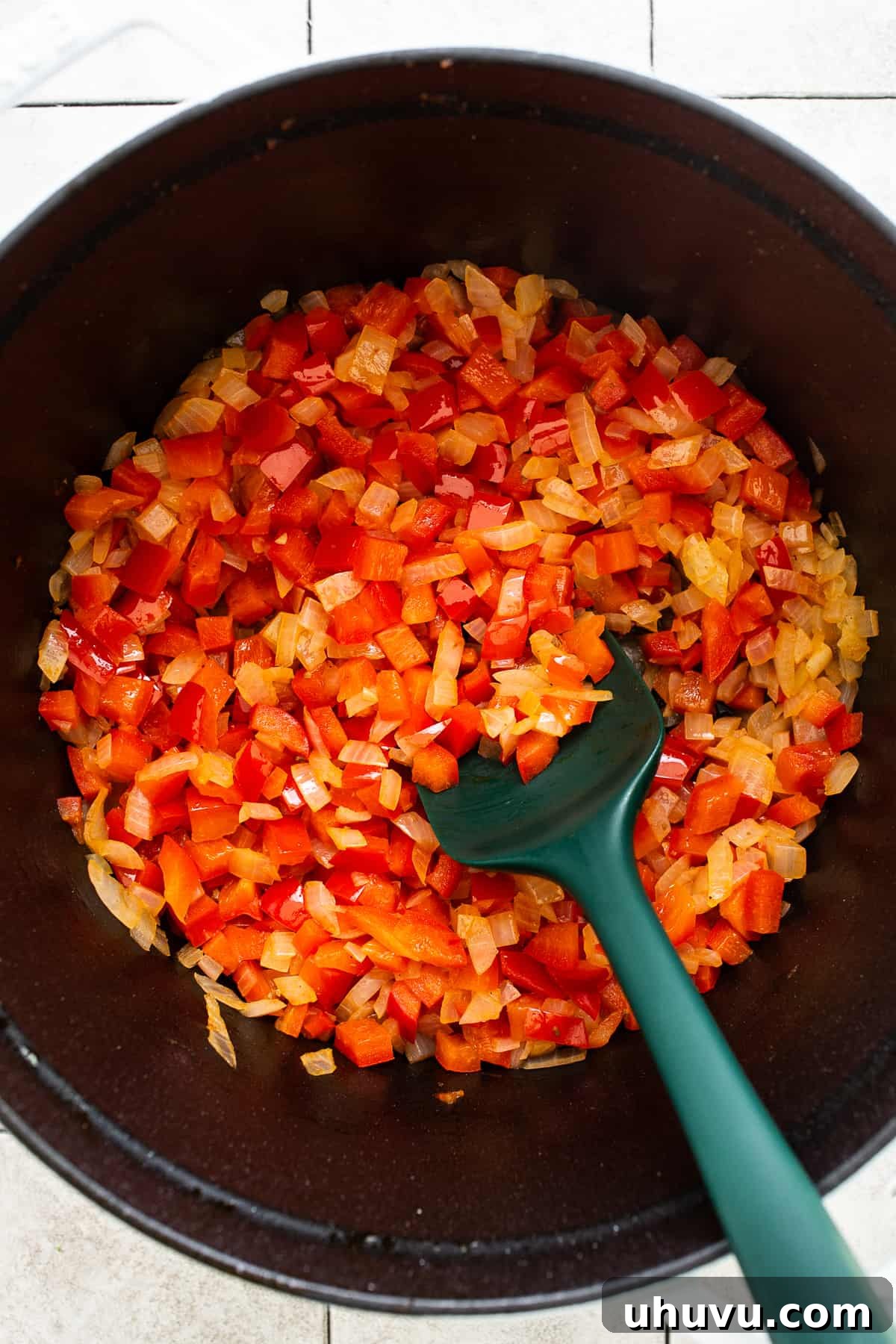 Chorizo Kick Chili 5 Vibrant red bell peppers and diced white onions sizzling in olive oil within a large pot, beginning to soften and release their sweet aromas, forming the flavorful base of the chili.