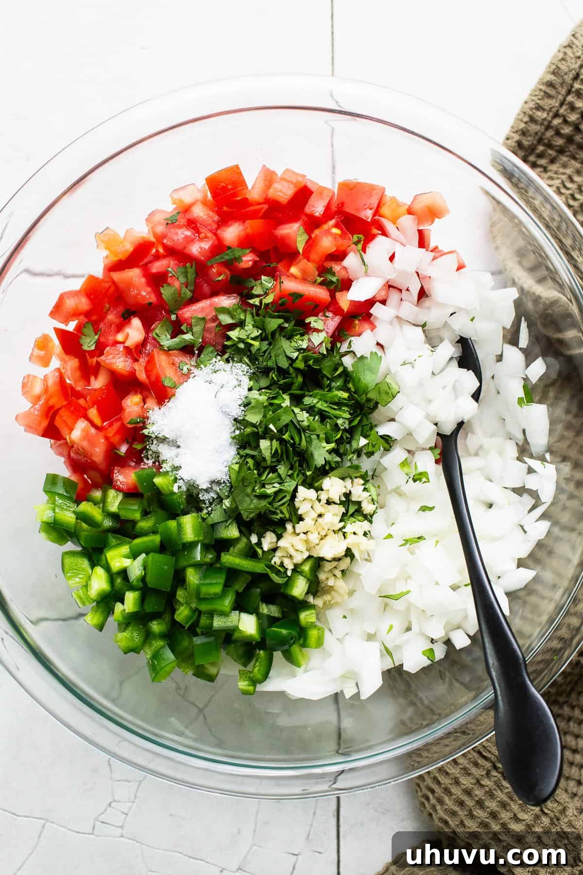 Fresh Salsa Fiesta 4 Finely diced tomatoes, onions, jalapeños, garlic, and salt added to a bowl, ready to be mixed into a homemade pico de gallo.