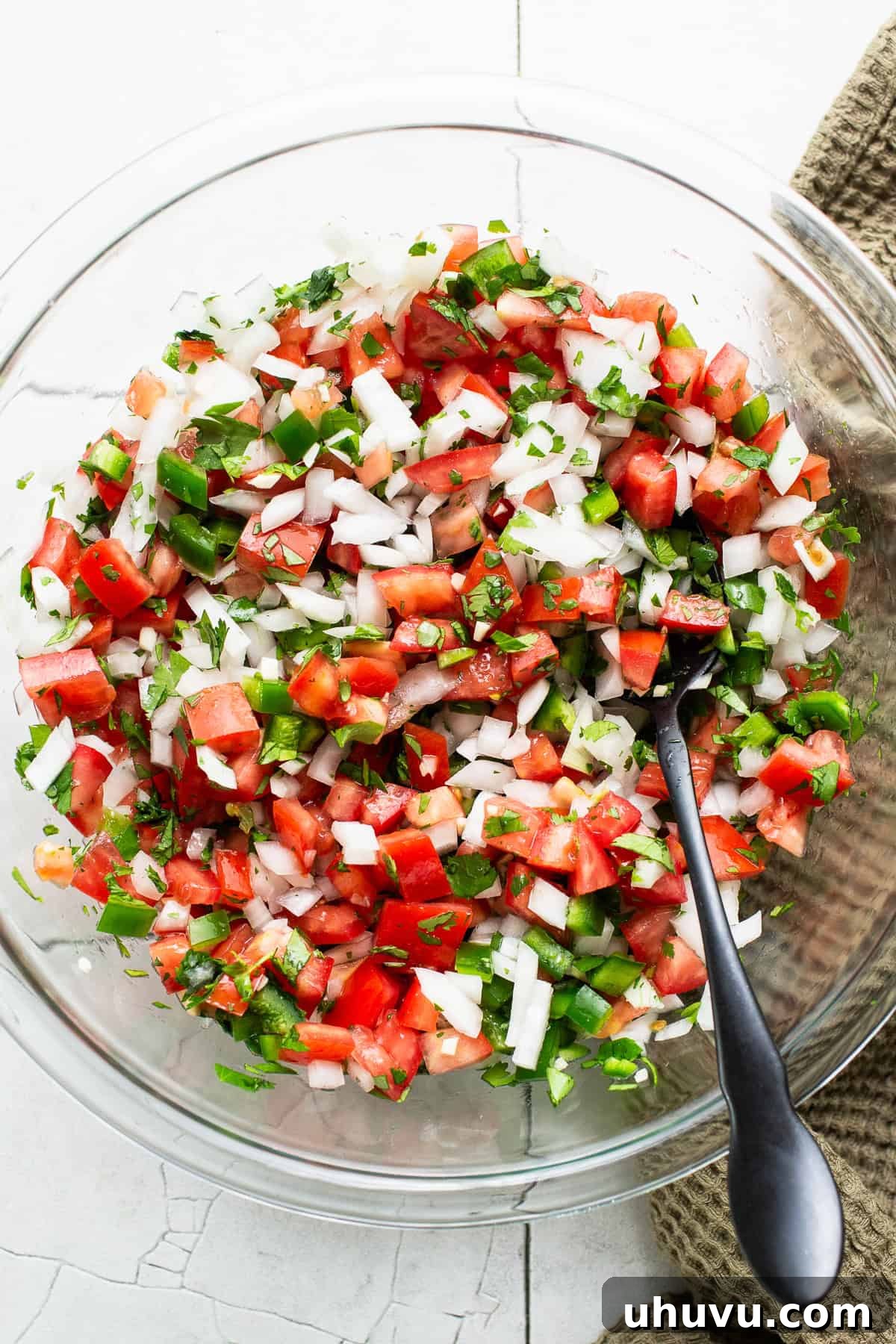 Fresh Salsa Fiesta 5 All the fresh pico de gallo ingredients, including tomatoes, onions, jalapeños, and cilantro, tossed together in a clear glass bowl, showcasing their vibrant colors and chunky texture.