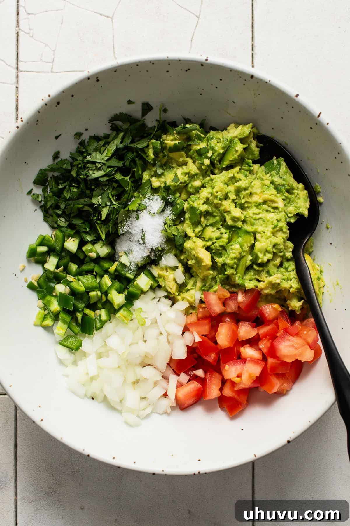 Perfect Guacamole 5 Smashed avocado, cilantro, jalapeño, onion, tomato, and salt in a bowl, before mixing.