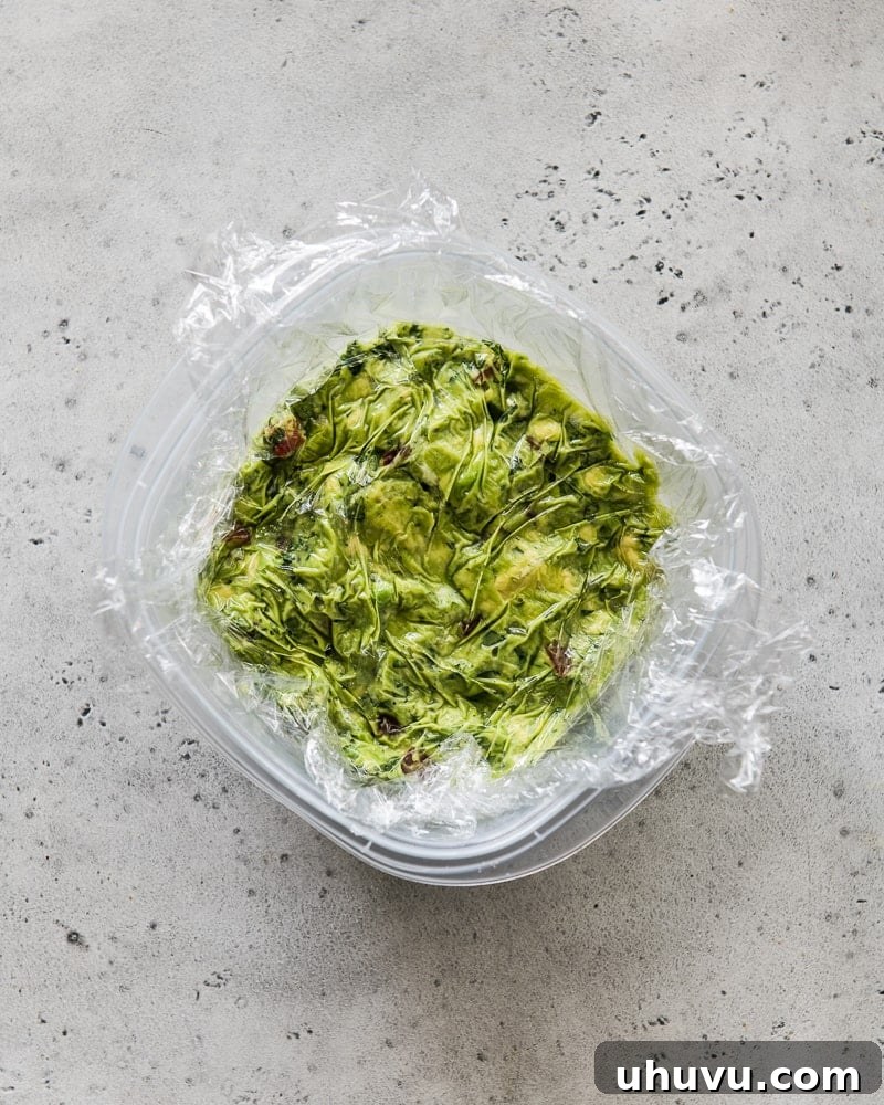 Perfect Guacamole 6 Guacamole being stored in a container with plastic wrap tightly covering its surface.
