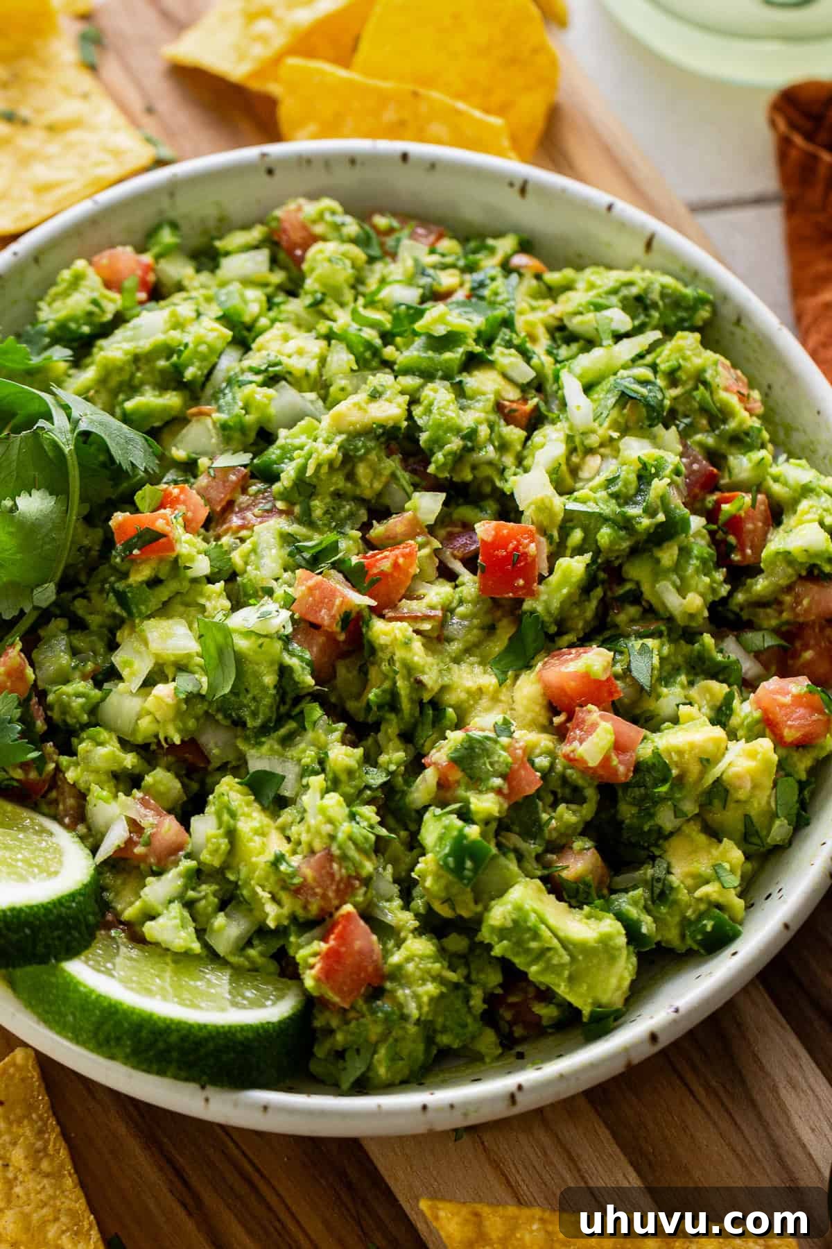 Perfect Guacamole 8 A bowl of fresh guacamole served with crispy tortilla chips, garnished with cilantro.