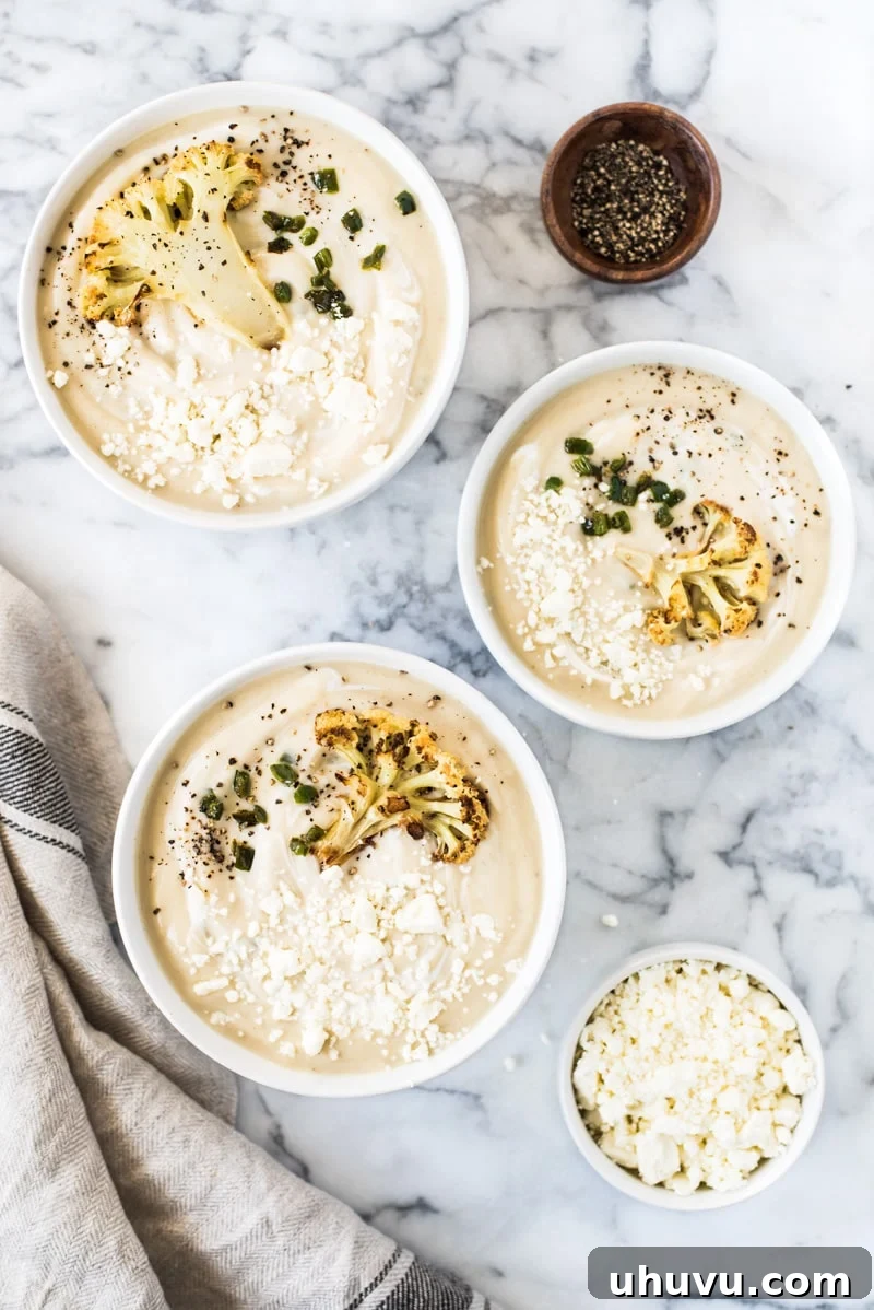 A bowl of creamy Roasted Cauliflower Soup, beautifully garnished with crispy fried jalapeños and a sprinkle of fresh black pepper, highlighting its wholesome ingredients.