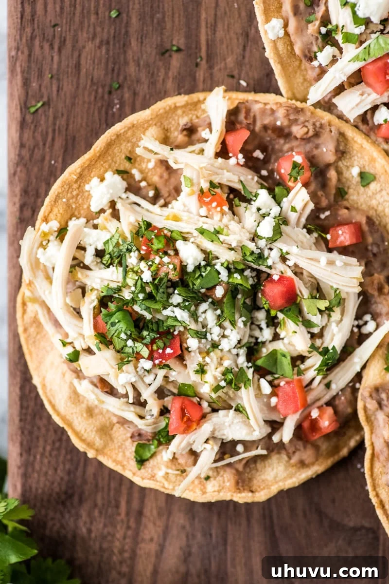 These crispy and crunchy Slow Cooker Salsa Verde Chicken Tostadas are topped with a layer of delicious refried beans, salsa verde chicken, tomatoes, cilantro, queso fresco and avocados.