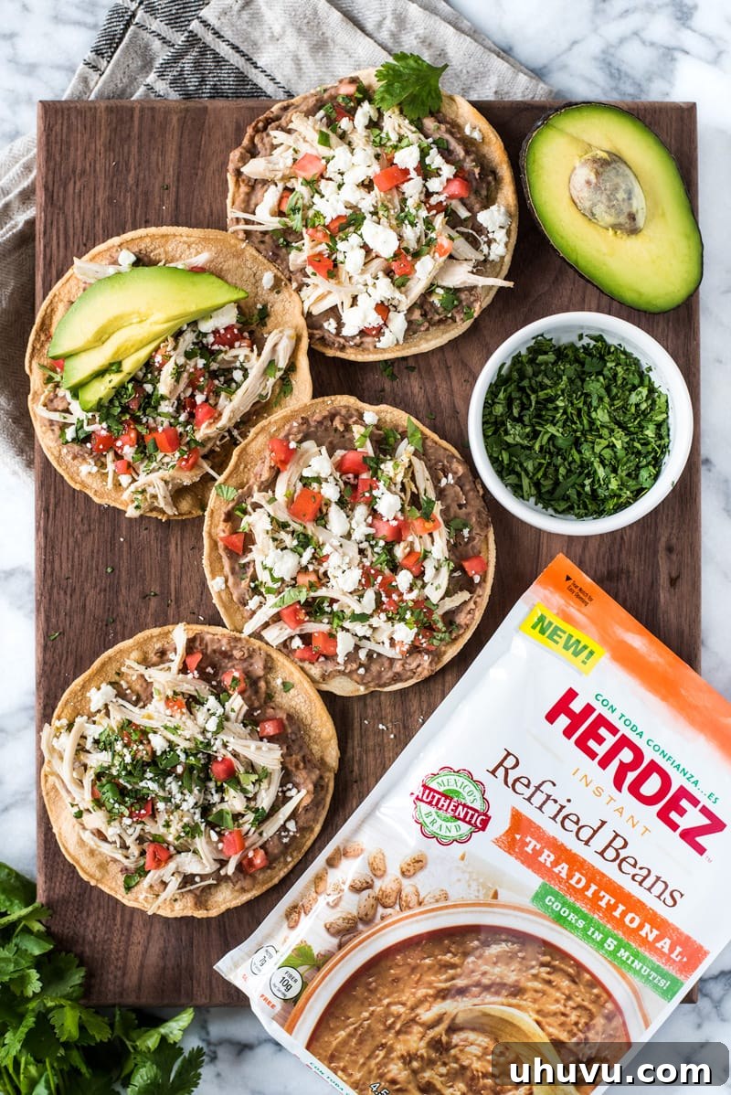 These crispy and crunchy Slow Cooker Salsa Verde Chicken Tostadas are topped with a layer of delicious refried beans, salsa verde chicken, tomatoes, cilantro, queso fresco and avocados.