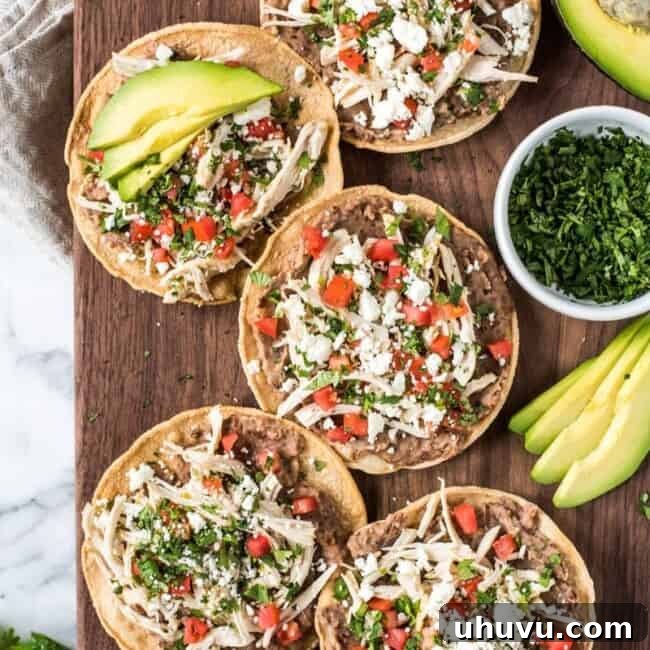 These crispy and crunch Slow Cooker Salsa Verde Chicken Tostadas are topped with a layer of delicious refried beans, salsa verde chicken, tomatoes, cilantro queso fresco and avocados.