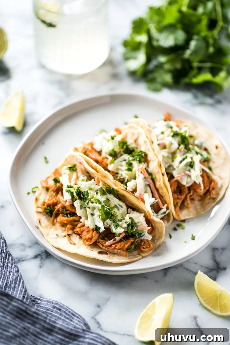 Tender Slow Cooker BBQ Pulled Pork Tacos with a fresh cilantro lime coleslaw topping, ready to serve.