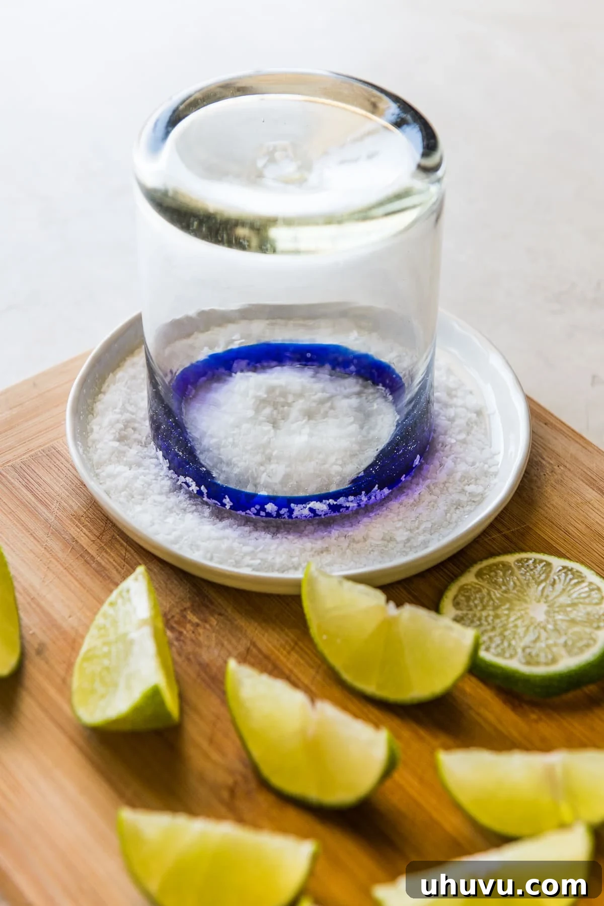 Crafting the Perfect Margarita 3 A blue-rimmed margarita glass being dipped in salt and lime juice, preparing for the perfect classic margarita.