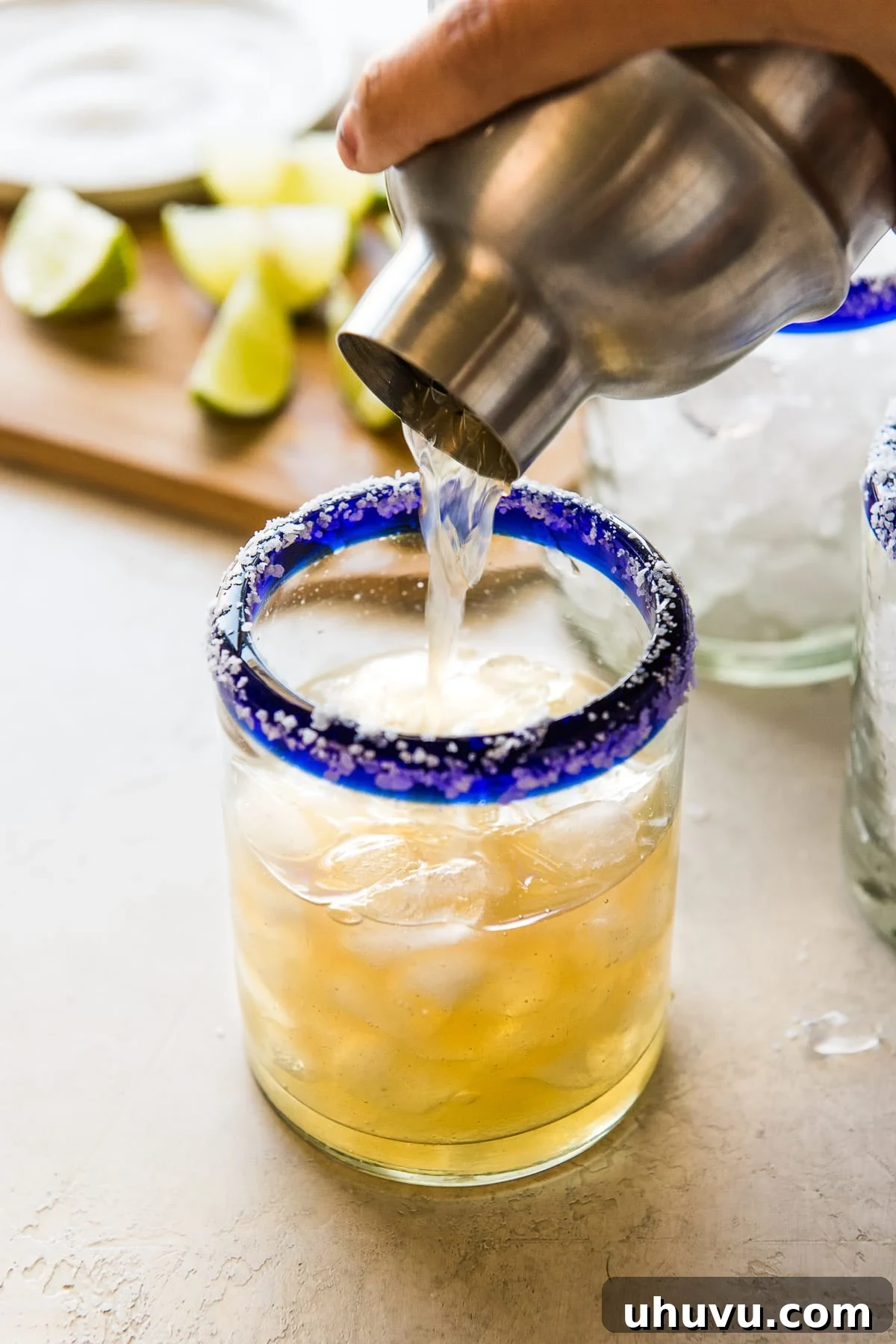 Crafting the Perfect Margarita 4 A cocktail shaker pouring a classic margarita into a perfectly rimmed glass, showcasing the refreshing drink being made.