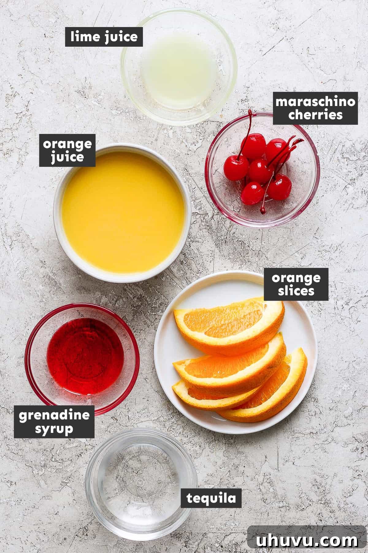 Liquid Dawn 3 Fresh ingredients laid out on a table for making Tequila Sunrise: oranges, lime, a bottle of tequila, and grenadine.