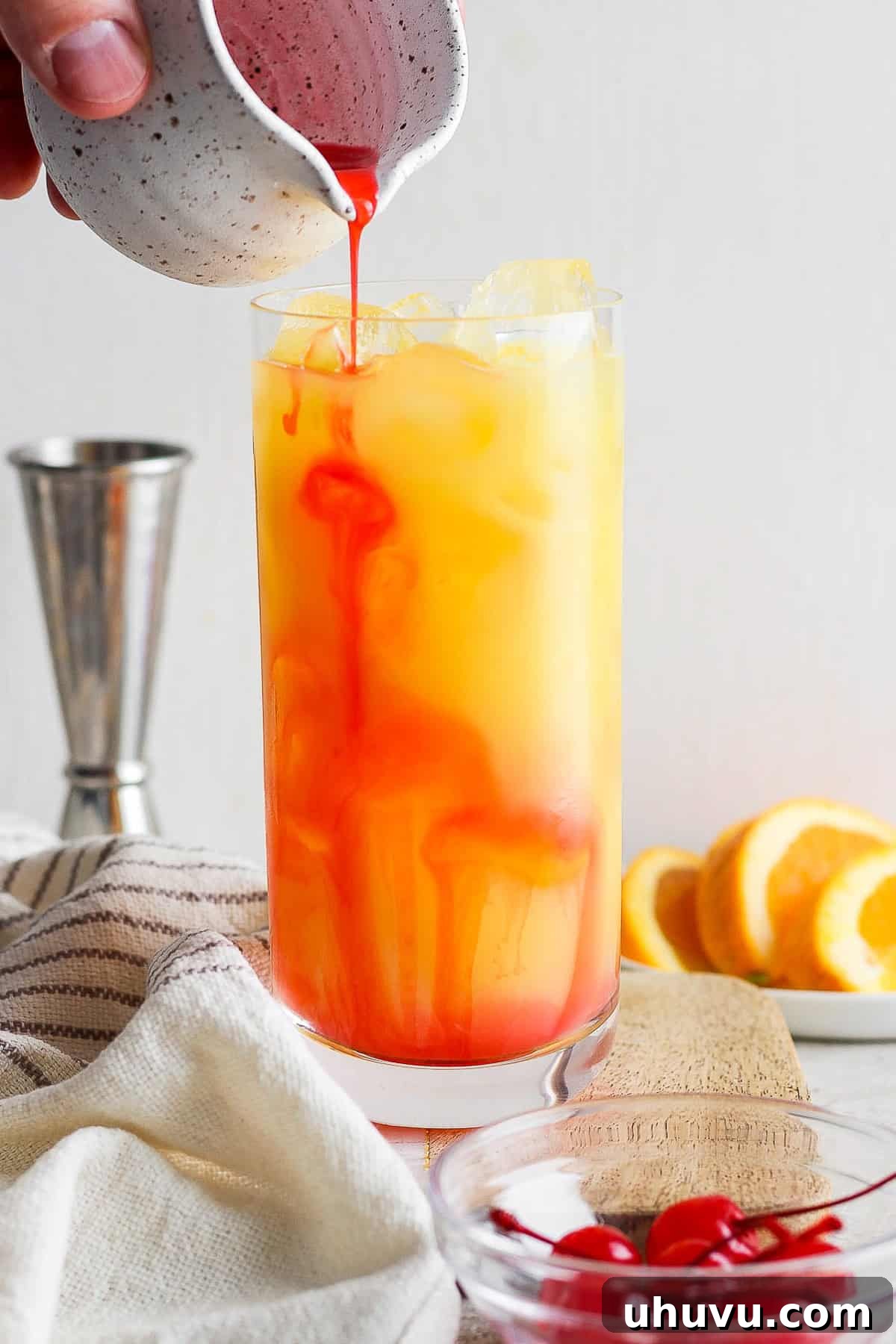 Liquid Dawn 6 A delicate stream of grenadine syrup being poured slowly down the inside of a highball glass, creating the signature layered effect.
