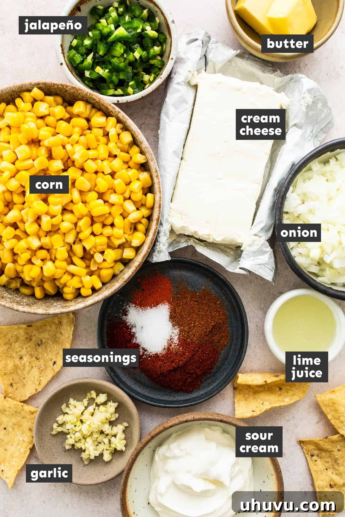 Elote Fiesta Dip 3 All the fresh ingredients for Mexican corn dip laid out on a wooden table, including corn, cream cheese, jalapeños, onions, garlic, and spices.