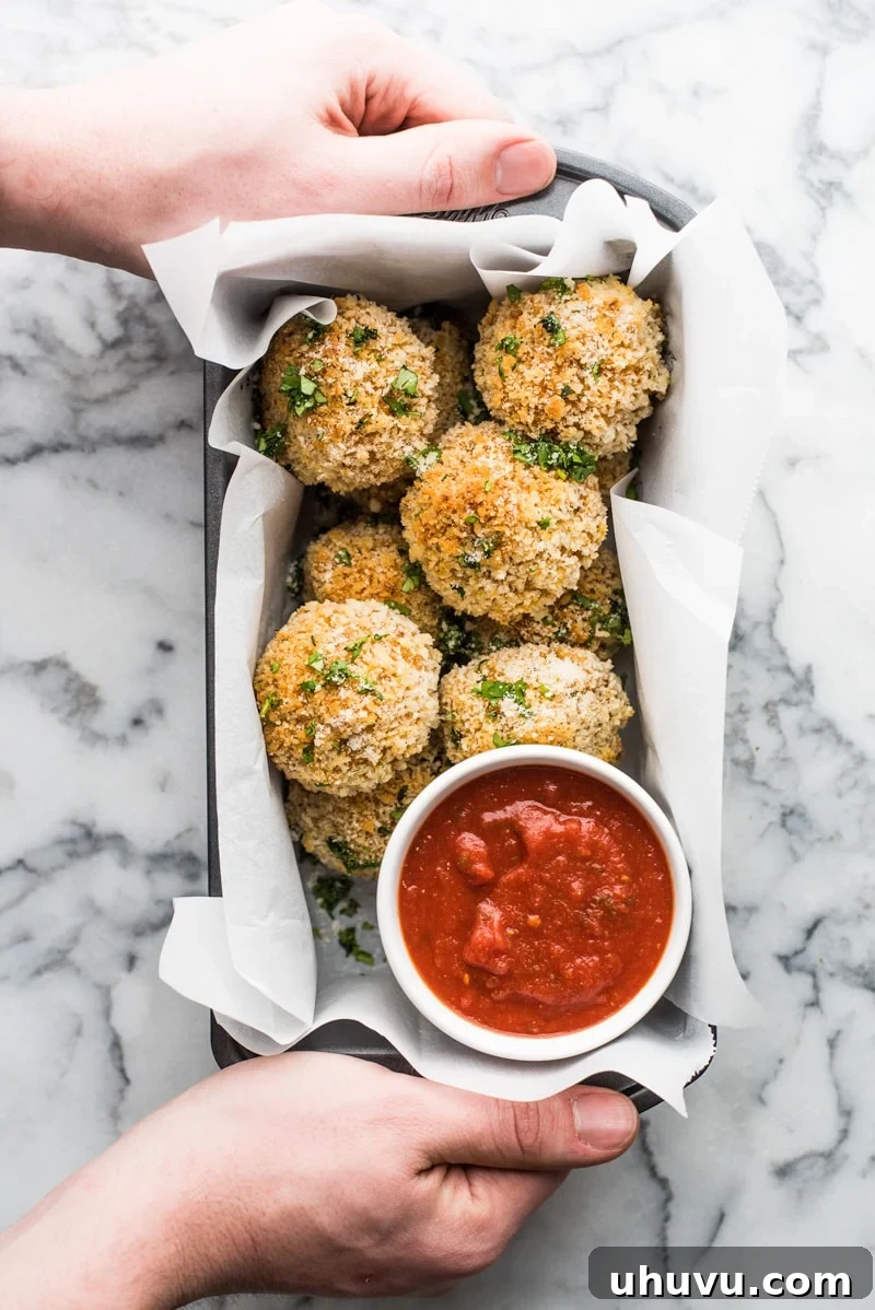 Zesty Fiesta Rice Bites 13 A serving of baked Mexican arancini rice balls, garnished with fresh cilantro and Parmesan, accompanied by a rich spicy marinara sauce.