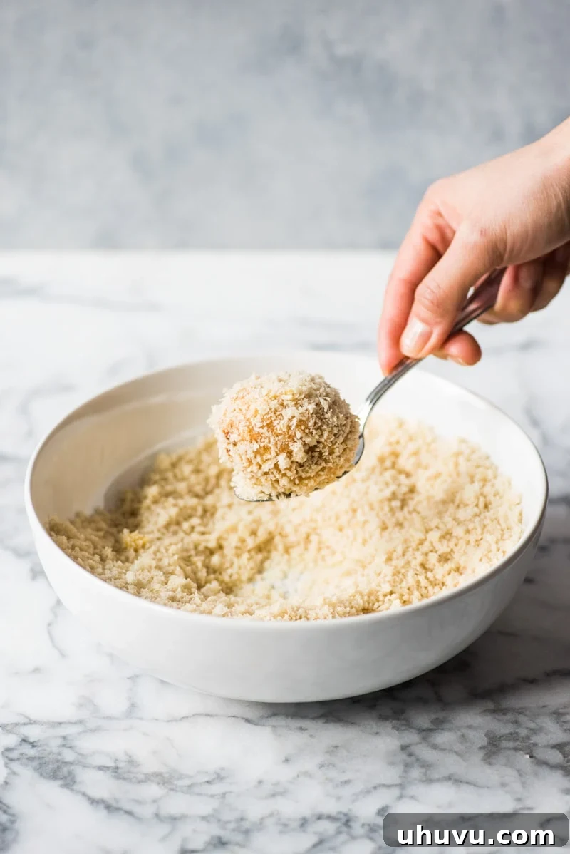 Zesty Fiesta Rice Bites 8 Carefully removing the fully breaded arancini rice ball from the panko, ready for baking.